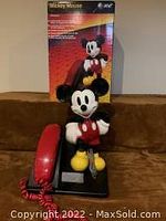 Photo of the Mickey Mouse telephone new in box with the phone sitting in front of the box, showing the full Mickey Mouse figure and the handset with the cord.