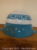 Two Pyrex Cinderella bowls, one larger solid blue with Blue Horizon pattern band and smaller with pattern, shown stacked