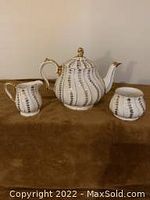 Front view of the Sadler tea set: teapot with lid, creamer, and sugar bowl displayed on brown background