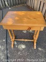 Front and top view of the small pine side table showing its rectangular wooden top with some minor wear.
