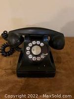Front view of black Northern Electric rotary dial telephone showing rotary dial and handset on cradle.