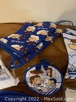 Photo of Tetley Tea Folk oven mitts, pot holder, and tea towels showing colorful character designs on blue fabric.