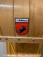 Close-up of St Ferdinand brand logo on wooden toboggan showing vintage sled illustration and red shield background.