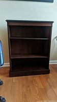 Front view of the wood bookcase showing two shelves and solid base.