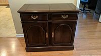 Front view of cherry hardwood buffet with two drawers and two cabinets with brass hardware.