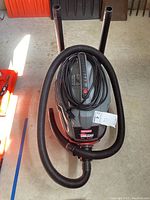 Top and front view of Craftsman Clean n Carry shop vacuum with attached hose and power cord, showing label with model and power specs.