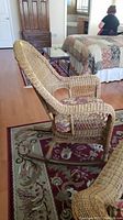 Front and side view of the faux wicker rocking chair with floral cushioned seat on a patterned rug, nearby bed and furniture visible.