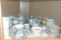 Image showing an array of assorted tea cups, saucers, and a teapot with floral and geometric patterns in pastel colors, some metallic trim