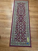 Full length top view of the runner on hardwood floor showing red and beige floral design