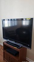 Front view of Sony LCD TV on wooden stand with remote beneath