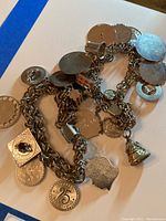 Photo showing two sterling silver charm bracelets with multiple attached charms in various shapes and designs.
