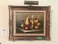 Framed oil painting still life with picture light mounted above, showing full painting and frame.