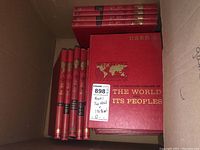 42 volumes of The Illustrated Library of the World and Its Peoples boxed in a cardboard container, displaying spines and covers showing regional titles and red hardcover with gold embossing.