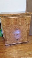 Front view of the tall wooden dresser with distinct wood grain pattern and brass handles.
