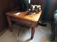 First wood side table with scratches visible on surface, drawer front, and turned legs