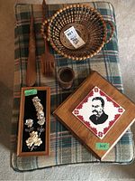Top view of wood plaque with portrait tile, wooden cup, back scratcher, shoehorn, round beaded basket, and framed 3D flower art.
