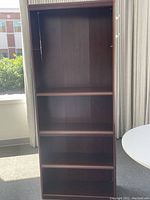 Front view of the brown 4-shelf bookcase showing the four shelves and the interior back panel.