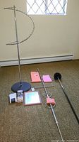 Photo showing tall metal towel rack, smaller towel rack, pink towels, black duster, framed mirror and part of boxed items.