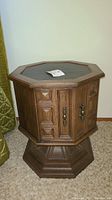 Full view of an octagonal wooden bedside table showing the cabinet doors and base.