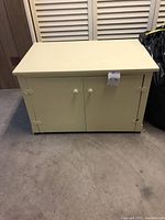 Front view of beige cabinet with closed double doors and round knobs