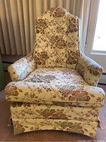 Front view of the floral patterned armchair showing seat cushion and armrests, fabric features multicolor flowers on an ivory background.