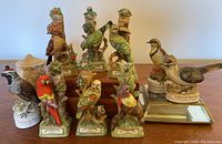 Photo showing multiple vintage decorative bird figurines including Lionstone Whisky labeled bases and a bottle labeled California Special.