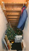 Entry view of storage space with Christmas tree, wreath, ornaments, cooler, garment bag, hangers visible