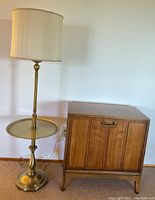 Brass floor lamp beside wood record cabinet