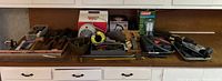 Full view of the shop items laid out on a white counter including the drum auger, several hand tools, shop vac attachments, and boxed lantern.