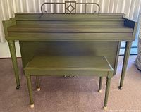 Front view of olive green upright piano with matching bench, showing closed piano top and legs