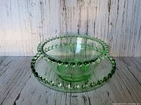 Clear front view showing the light green glass bowl with hobnail edge sitting on matching saucer with the same decorative edge detail.