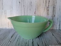 Side view of the pale green Fire King jadeite glass batter bowl showing handle and pour spout.