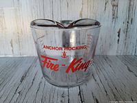 Front view of clear glass measuring cup with red Anchor Hocking Fire-King logo and measurement markings.