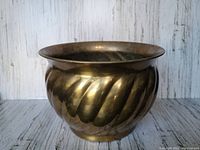 Front and side view of the large vintage brass planter showing swirl pattern and patina on the exterior surface
