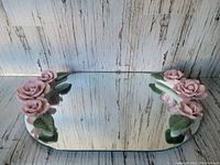 Top view of rectangular mirrored tray with two ceramic rose handles featuring light pink roses and green leaves.