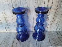 Pair of hollow cobalt blue glass candlesticks displayed side by side showing rounded tiered design and stable base.