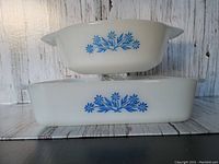 Stacked view showing exterior blue floral design of round and square milk glass dishes