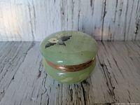 Image of round green alabaster jewellery box with floral painting on lid and gold-tone band