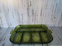 Rectangular vintage Indiana Glass relish tray in avocado green with ribbed edges and four divided compartments, photographed against rustic wooden backdrop.
