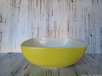 Side view of the vintage yellow Pyrex ovenware showing rounded square shape and white interior