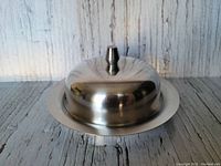 Closed view of the stainless steel round butter dish with cover knob.