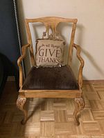 Front view of wood framed armchair with velvet seat and burlap pillow resting on it