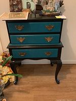Front view of the painted chest showing three drawers with brass tone handles and cabriole legs.