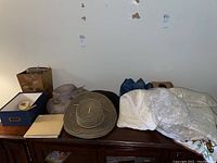 Wide view of hats, grooming set, and fabric items laid out on wooden dresser