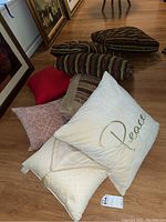 Group of 8 decorative pillows in various colors and patterns displayed on wooden floor.