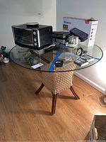 Full view of the glass top table showing the glass surface, wooden legs, and woven rope wrapped around the base frame.