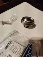 Single nickel cabinet/drawer pull shown alongside mounting screw and original packaging with Amerock label visible.