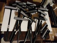 Multiple black plastic handheld squeegees with 8 inch rubber and mesh heads laying on a surface.