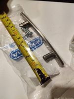 Close-up image of one nickel finished long bar cabinet/drawer pull with measuring tape showing length approximately 5 inches.