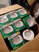 Box containing multiple unopened 4-inch LED retrofit light kits in green and white Sunco packaging, stacked neatly.
